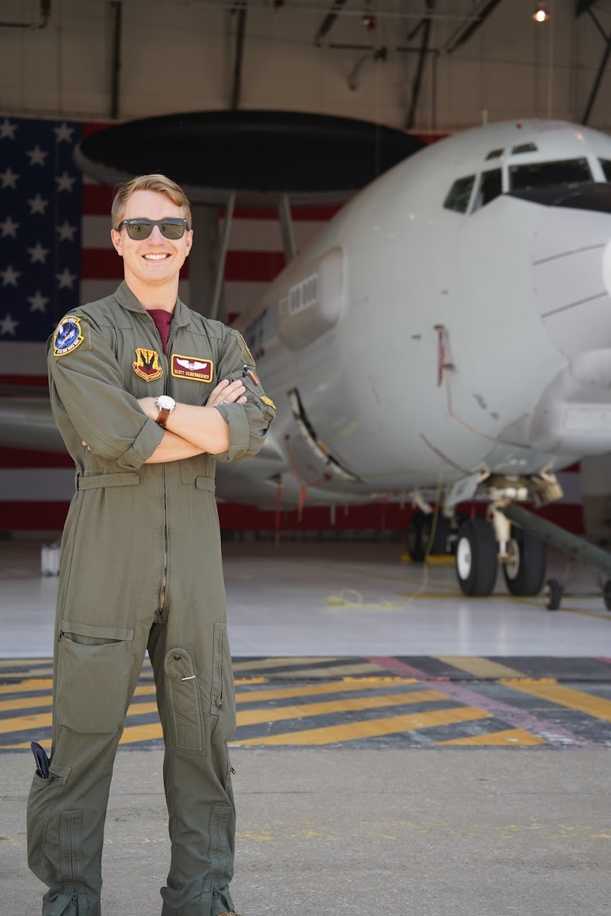 Scott Seidenberger in flight suit standing in front of a USAF E-3 AWACS aircraft.
